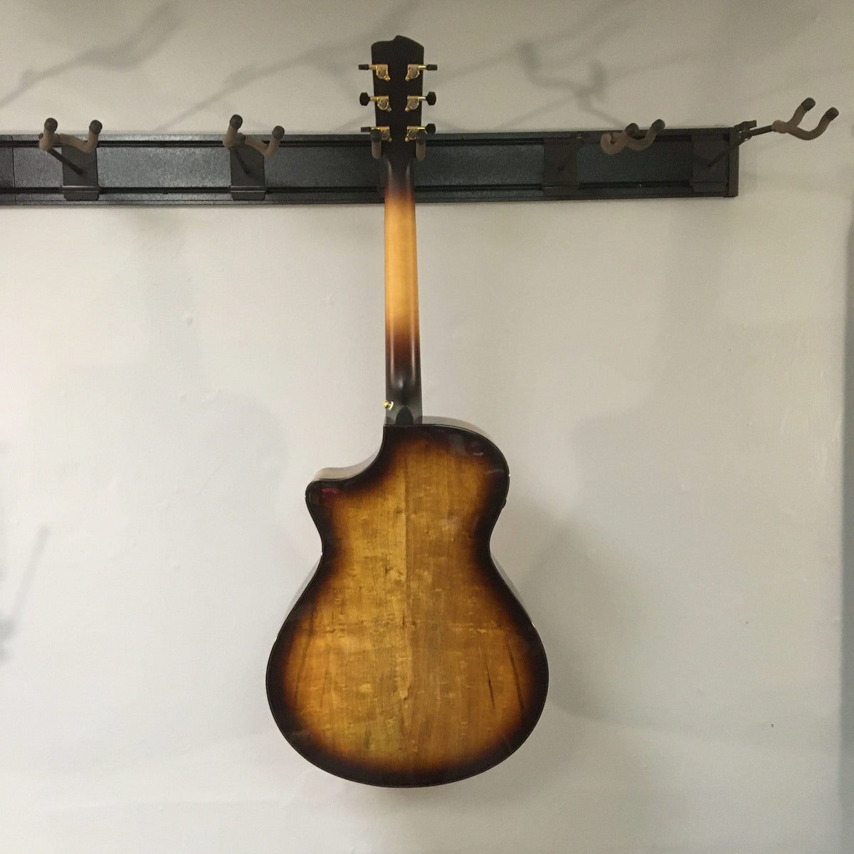 Breedlove Artista Pro Concerto Burnt Amber CE guitar displayed on a wall, featuring solid wood construction, brass inlays, and premium electronics.