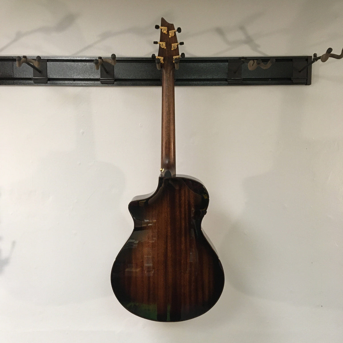 Breedlove Performer Pro Concert Aged Toner CE European-African Mahogany guitar mounted on a wall, showcasing its premium craftsmanship and solid wood construction.