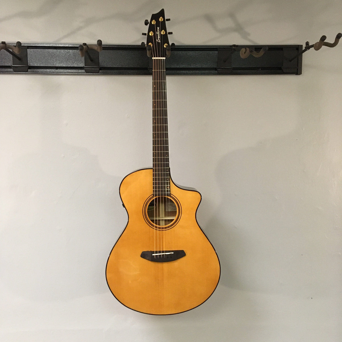 Breedlove Performer Pro Concert Aged Toner CE guitar with African mahogany and European spruce, displayed on a wall.
