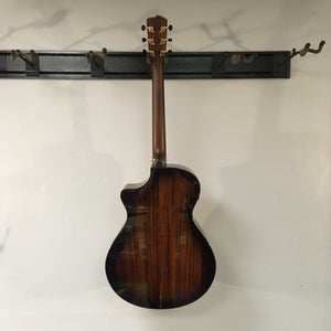 The Breedlove Performer Pro Concerto Aged Toner w/Gator Gigbag hangs on a wall rack, its elegant aged toner finish and gold tuning pegs showcasing the signature style of Breedlove acoustic guitars.