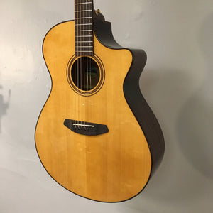 The Breedlove Performer Pro Concerto Aged Toner, featuring a cutaway body and rich acoustic tone, hangs elegantly in its Gator gigbag against a plain light-colored wall.