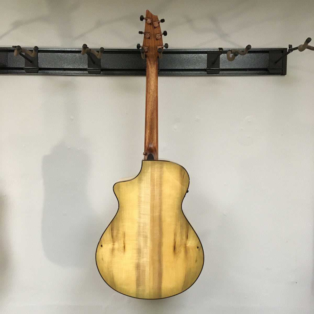 Breedlove Pursuit Exotic S Concert Sweetgrass CE B-Stock acoustic guitar mounted on a wall, highlighting its detailed craftsmanship and elegant design.