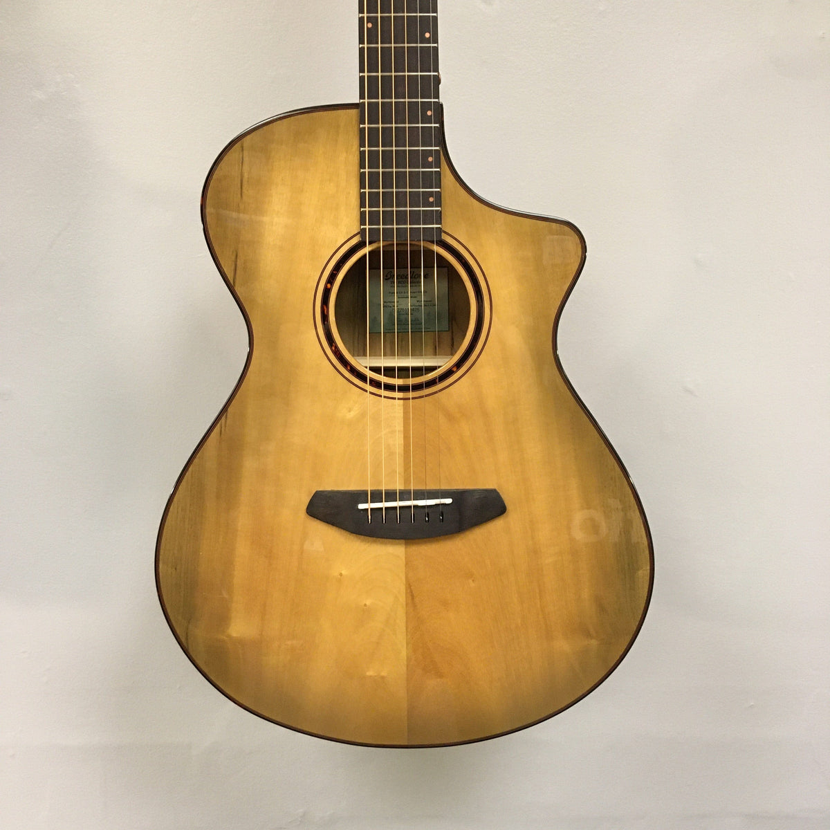 Close-up of a Breedlove Pursuit Exotic S Concert Sweetgrass CE B-Stock acoustic guitar, highlighting the strings and body craftsmanship.