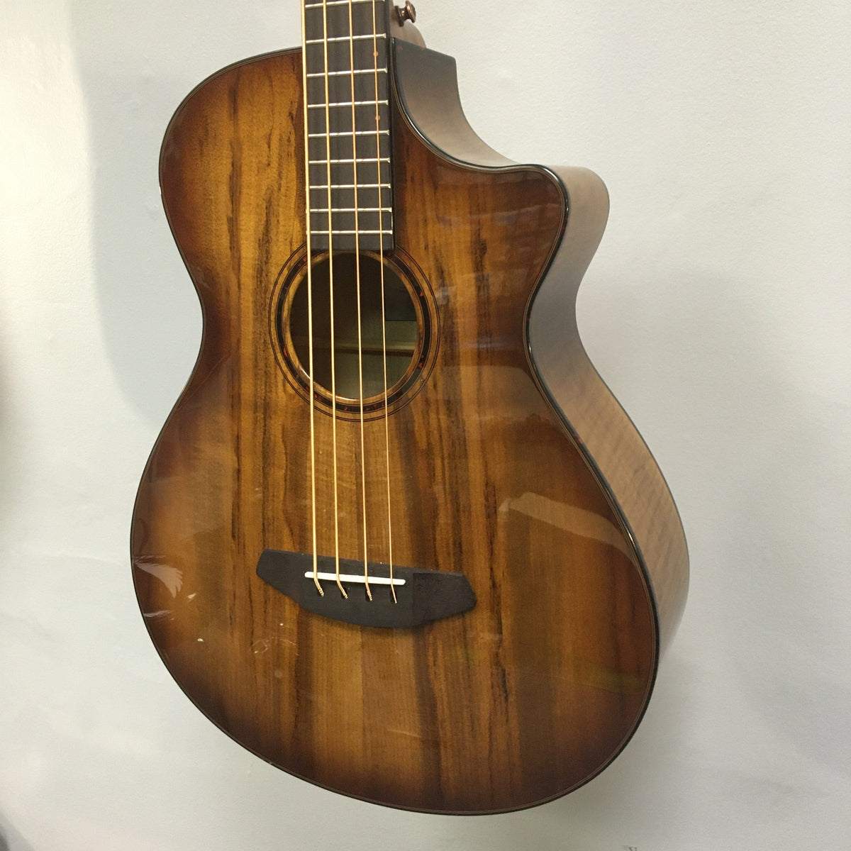 Breedlove Pursuit Exotic S Concerto Amber Bass CE B-Stock, close-up of strings and tortoise binding, highlighting finish blemishes.