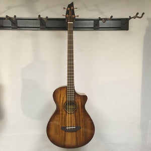 Breedlove Pursuit Exotic S Concerto Amber Bass CE B-Stock hanging on wall, showing close-up details of strings and body finish blemishes.
