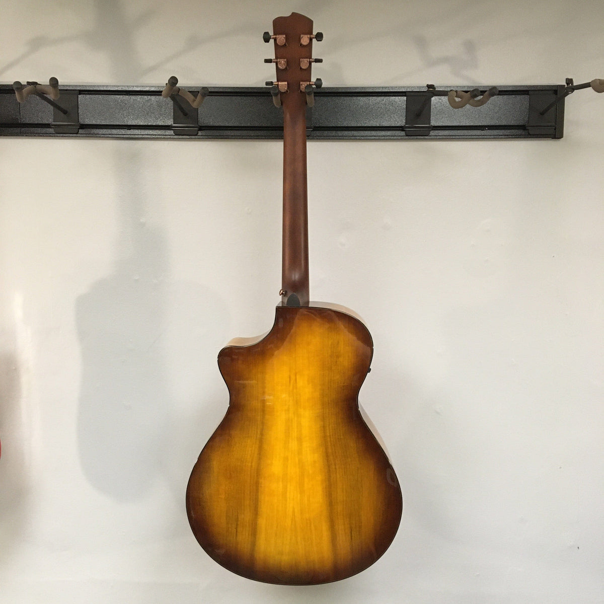 Breedlove Pursuit Exotic S Concerto CE Tiger's Eye Myrtlewood B-Stock acoustic guitar with minor cosmetic blemishes, hanging on a wall.