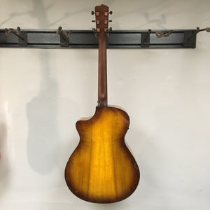 Breedlove Pursuit Exotic S Concerto CE Tiger's Eye Myrtlewood B-Stock acoustic guitar with minor cosmetic blemishes, hanging on a wall.