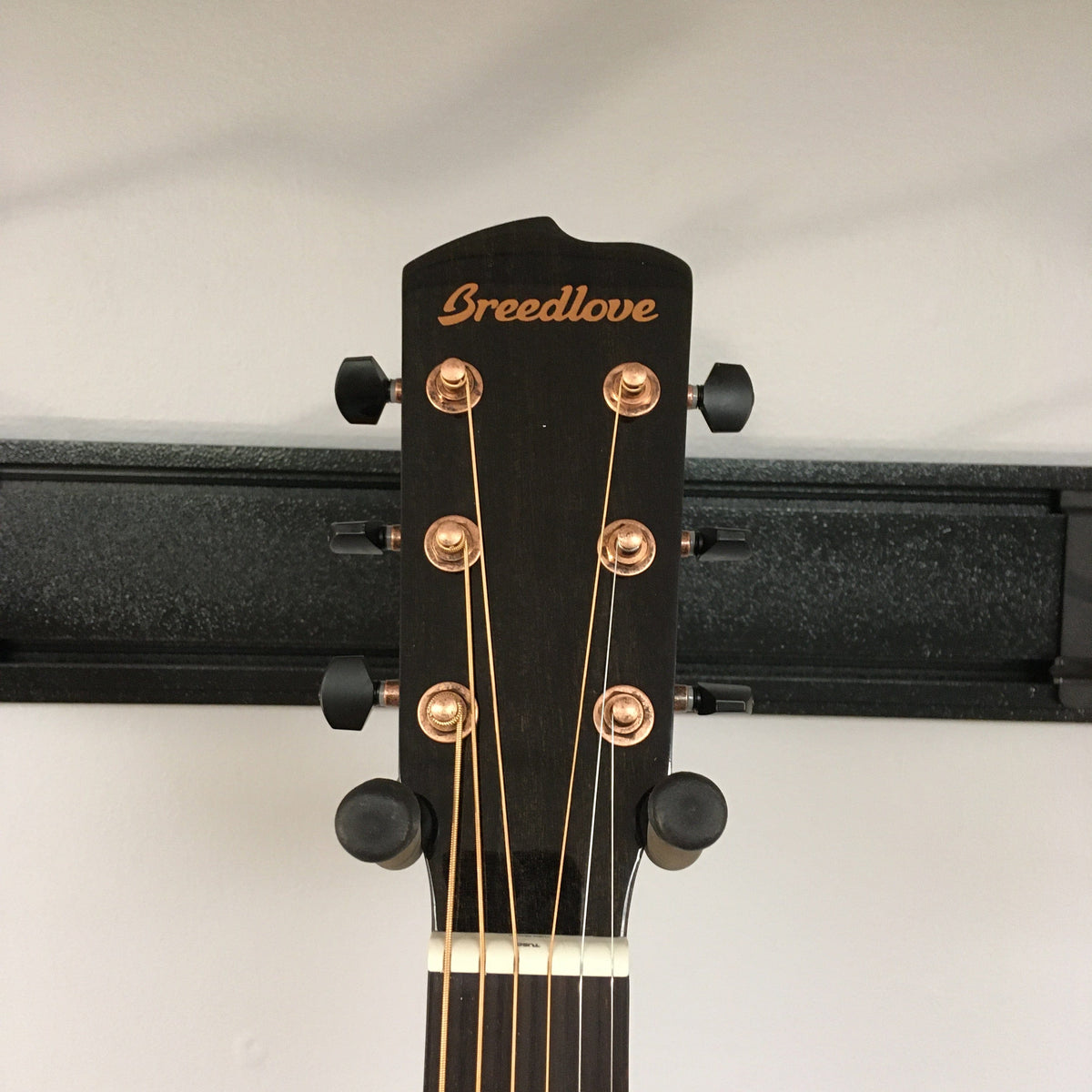 Close-up of the Breedlove Pursuit Exotic S Concerto CE Tiger's Eye Myrtlewood B-Stock guitar head with gold strings and copper tuners.
