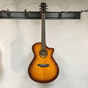 Breedlove Pursuit Exotic S Concerto CE Tiger's Eye Myrtlewood B-Stock acoustic guitar, hanging on a wall, showcasing a tortoise-bound finish.