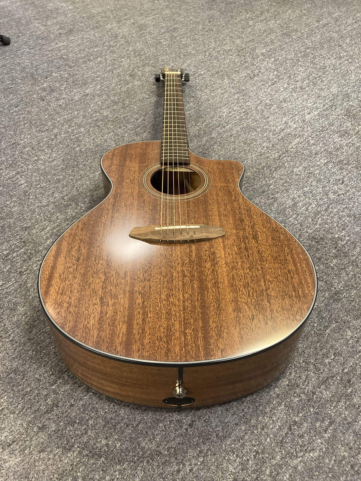 Breedlove Wildwood Concerto Satin CE guitar, solid African mahogany, close-up showing strings and neck, lying on the floor.