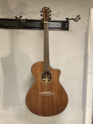 Breedlove Wildwood Concerto Satin CE Solid African Mahogany guitar mounted on a wall, showcasing its elegant body and craftsmanship.