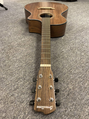 Breedlove Wildwood Concerto Satin CE guitar with solid African mahogany body, lying on the floor, showcasing its detailed craftsmanship and premium hardware.