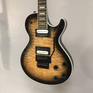 Dean Thoroughbred Select Quilt-top with Floyd Natural Black Burst, featuring close-up of guitar strings and hardware details on a wall display.