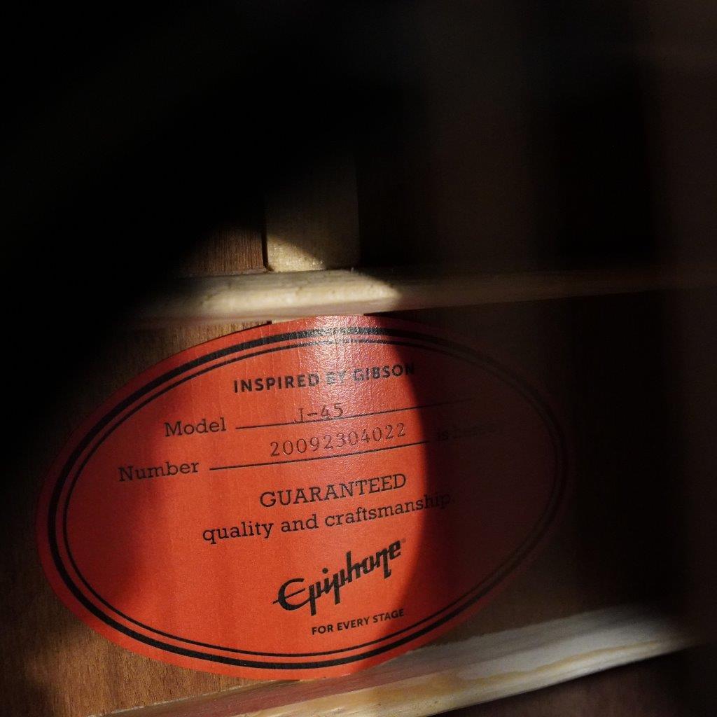 Epiphone Masterbilt J-45 Aged Vintage Sunburst Gloss, featuring solid wood construction and a Fishman Sonicore pickup, displayed on a wood surface with a detailed label.