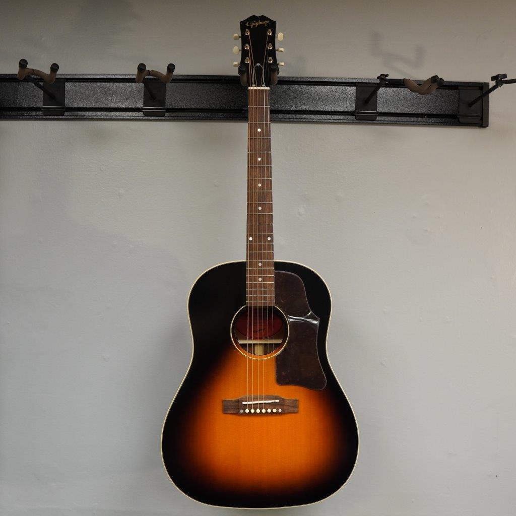 Epiphone Masterbilt J-45 Aged Vintage Sunburst Gloss, displayed on a wall, showcasing its solid wood construction and classic design.