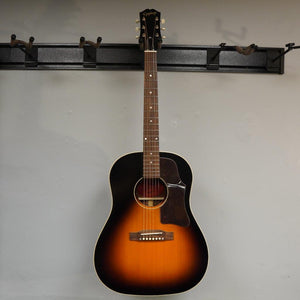 Epiphone Masterbilt J-45 Aged Vintage Sunburst Gloss, displayed on a wall, showcasing its solid wood construction and classic design.