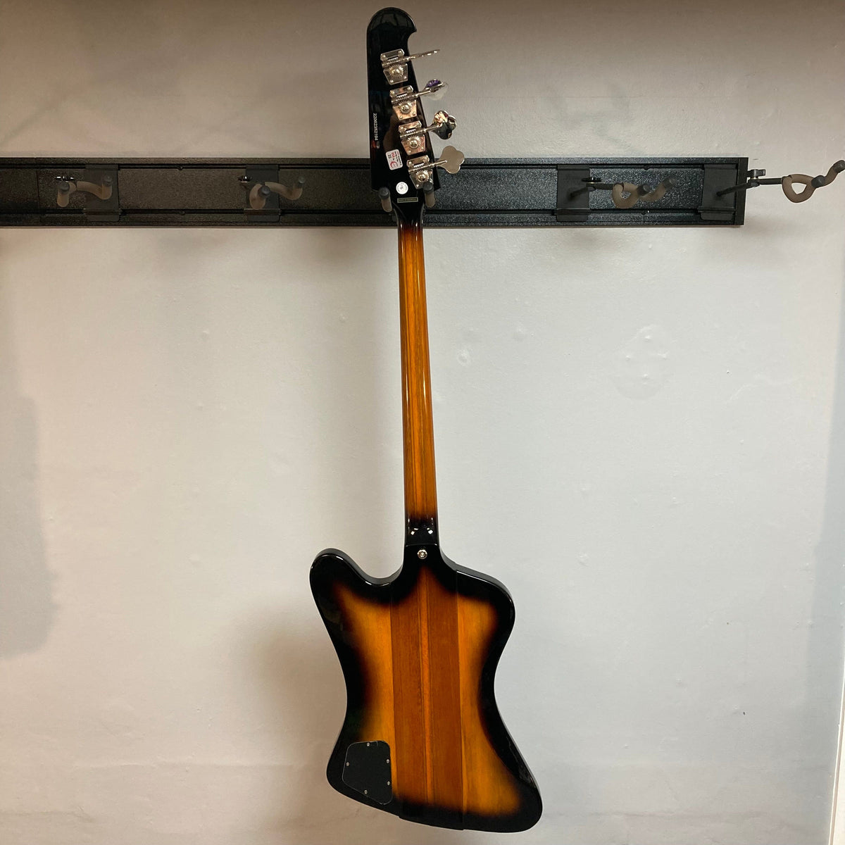 Epiphone Thunderbird IV Reverse Headstock Vintage Sunburst bass guitar on a wall rack, showcasing its unique zig-zag body and distinct headstock design.