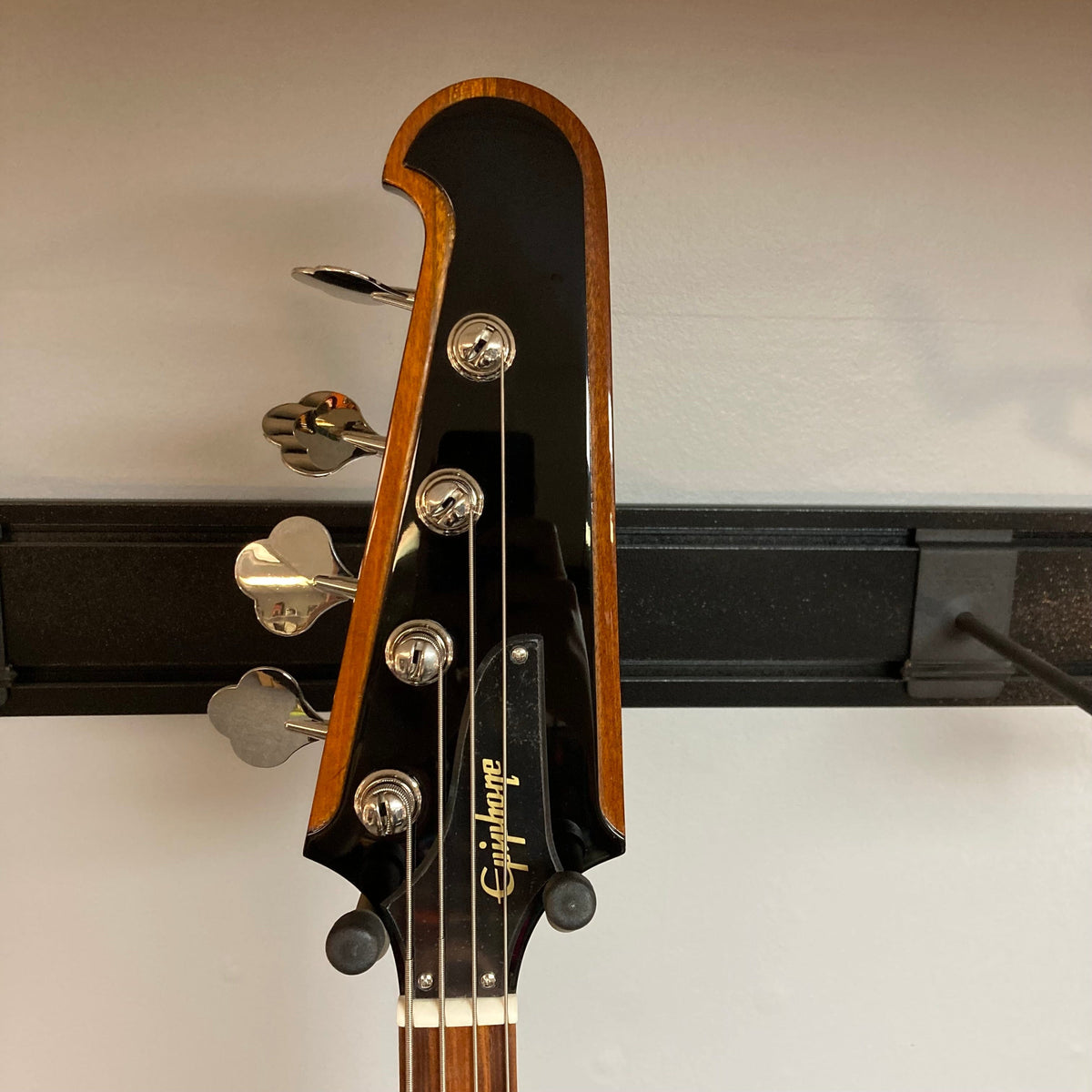 Epiphone Thunderbird IV bass guitar on a stand, featuring its iconic reversed body and headstock design.