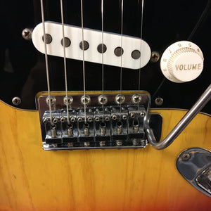Close-up of a 1976 Fender Stratocaster Sunburst guitar's strings and knobs, showcasing original parts and excellent condition.