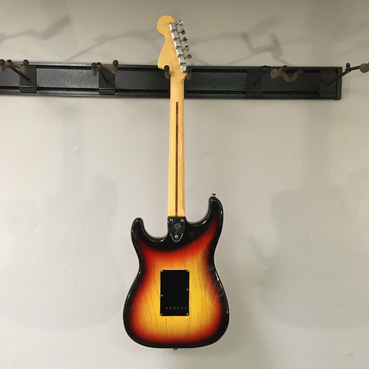 1976 Fender Stratocaster Sunburst, all original parts, displayed on a wall, close-up details of guitar body and neck, includes original case and paperwork.