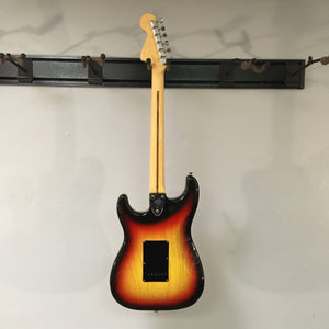 1976 Fender Stratocaster Sunburst, all original parts, displayed on a wall, close-up details of guitar body and neck, includes original case and paperwork.