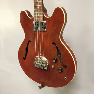 Close-up of a vintage Gibson EB-2C bass guitar, highlighting strings and body details, showcasing its relic look and modifications.
