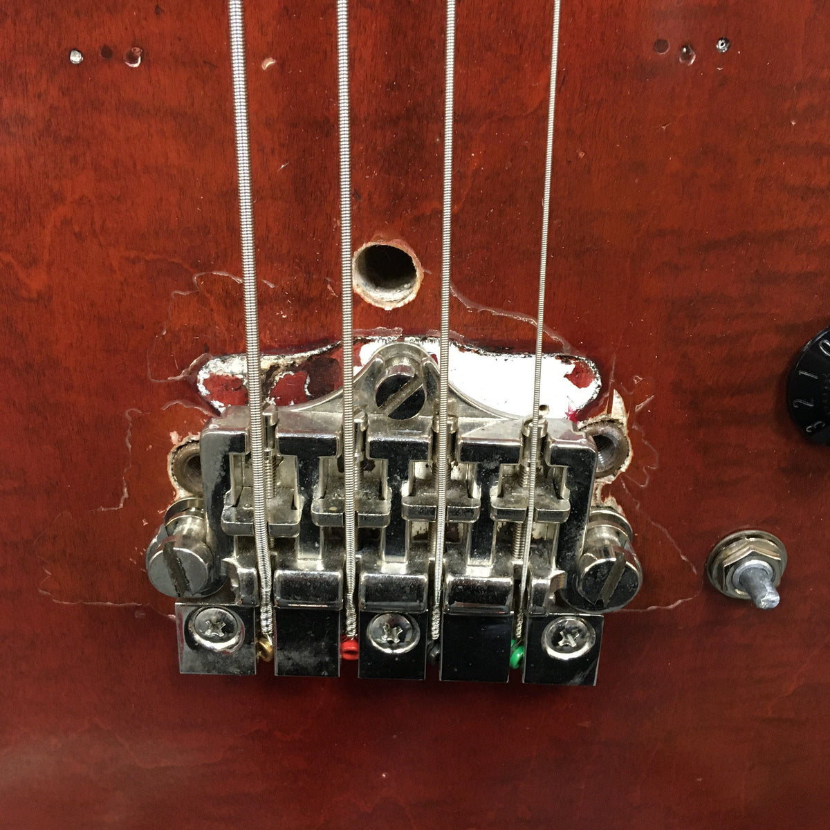 Close-up of a vintage Gibson EB-2C bass, showcasing its unique relic look and modifications.