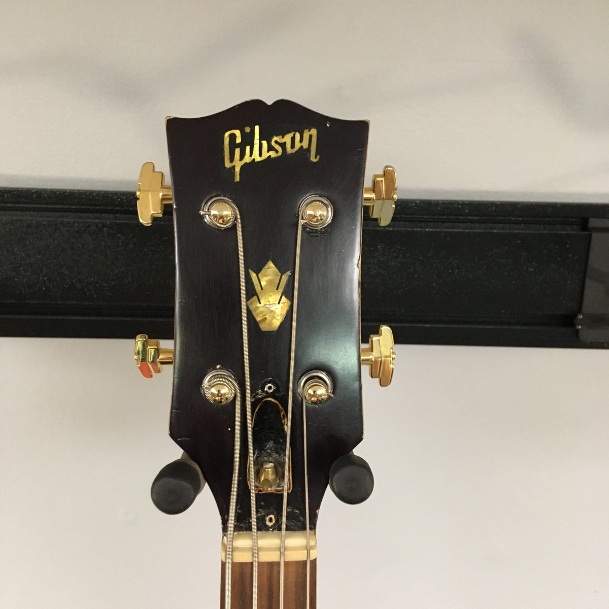 Gibson EB-2C bass headstock with gold knobs and strings, showcasing vintage design and craftsmanship.