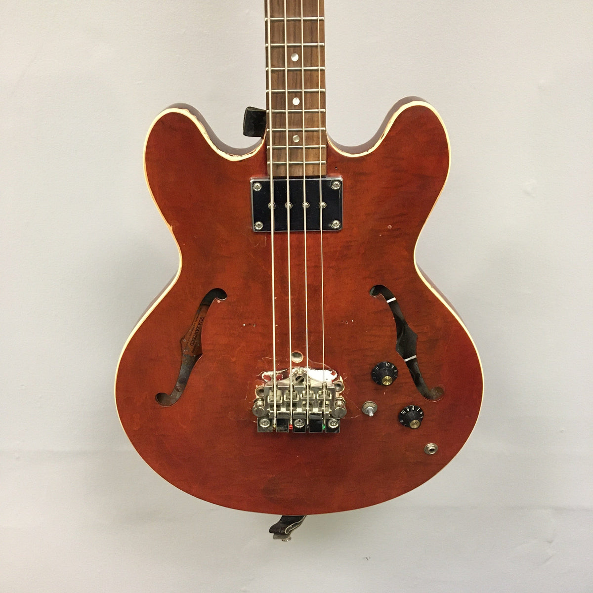 Close-up of a vintage Gibson EB-2C bass guitar, showing its well-worn condition and unique modifications.