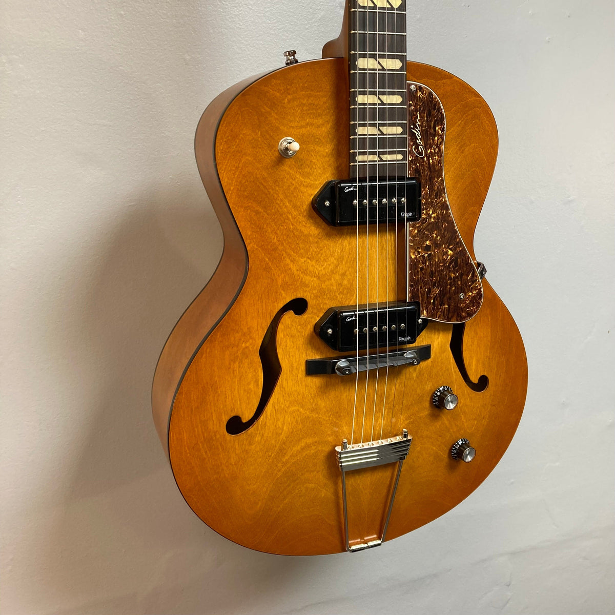 Godin 5th Avenue Jumbo P90 Harvest Gold guitar with redesigned headstock, large fret markers, and Godin logo, showcased for the 50th anniversary.