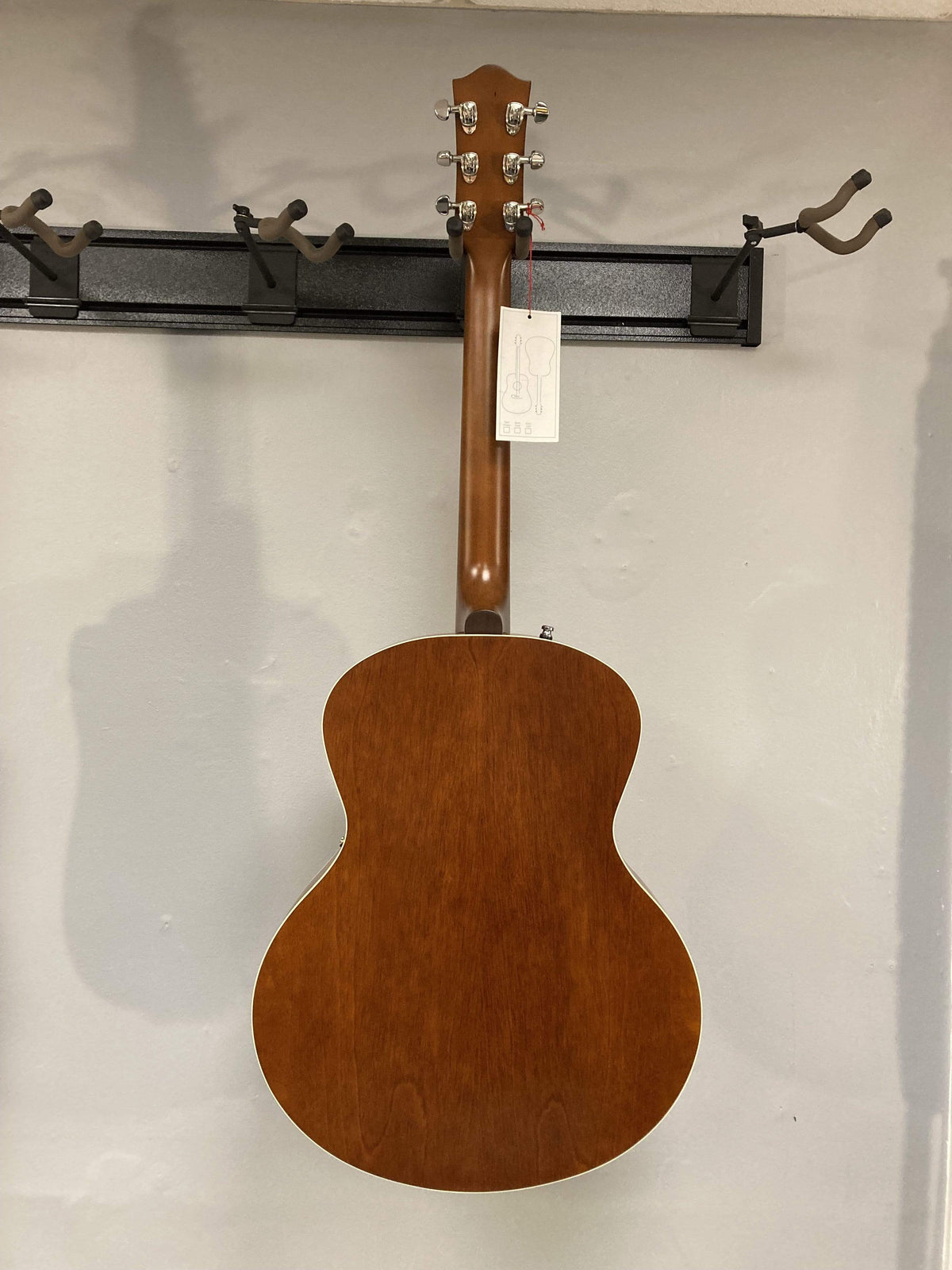 Godin 5th Avenue Kingpin P90 Cognac Burst archtop electric guitar displayed on a wall, showcasing its polished finish and intricate design.