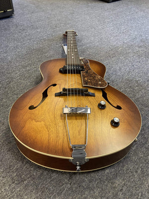Godin 5th Avenue Kingpin P90 Cognac Burst electric guitar on grey carpet, showcasing its polished finish and archtop design with visible strings and dials.