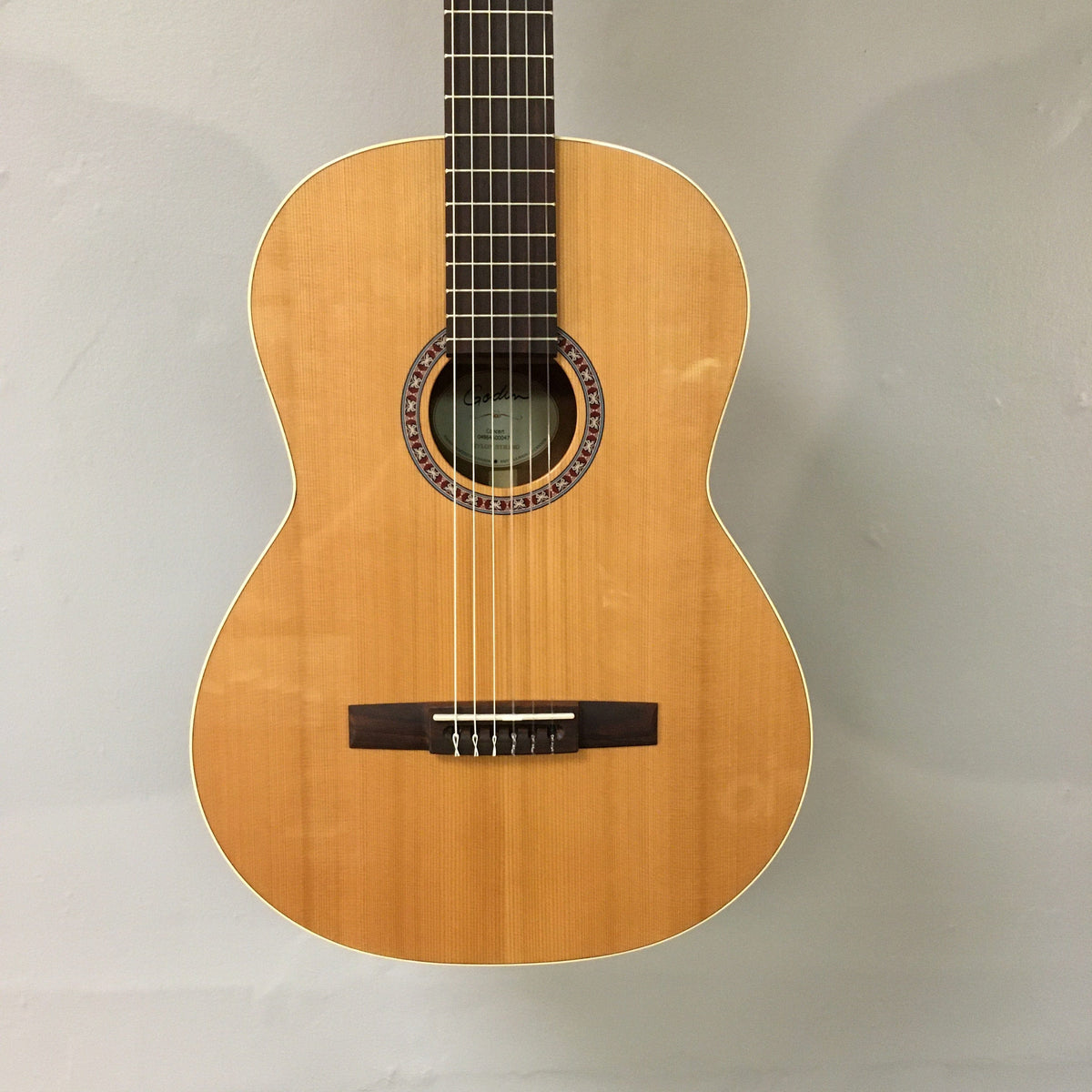 Close-up of the Godin Concert Nylon String Classical Guitar Open Box, showcasing its high gloss finish, solid cedar top, and nylon strings.