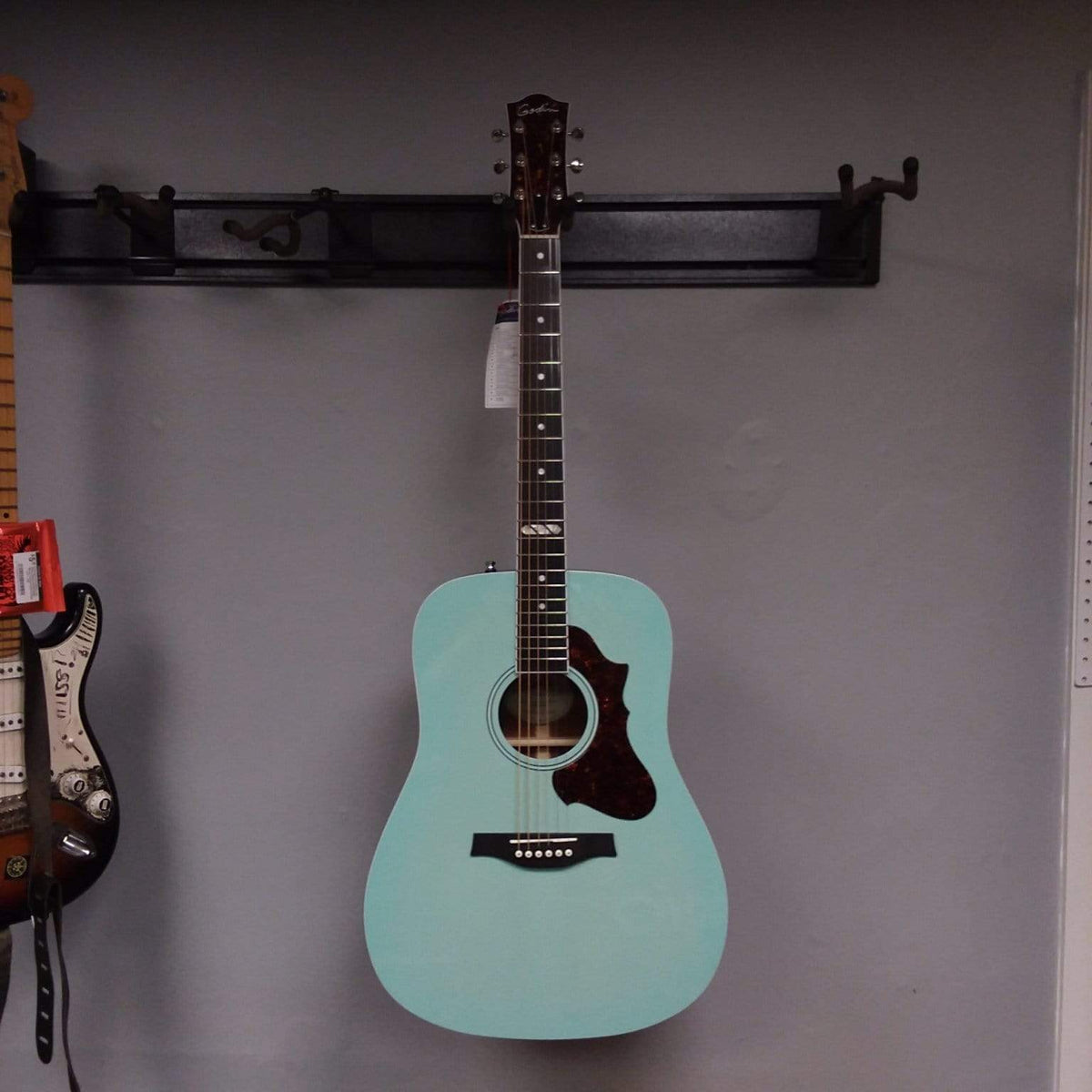 Godin Imperial Laguna Blue GT EQ acoustic guitar with mahogany body, spruce top, and LR Baggs Anthem system, mounted on a wall.