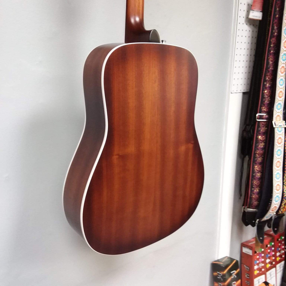 Godin Imperial Laguna Blue GT EQ acoustic guitar hanging on a wall, showcasing its solid mahogany body, Sitka spruce top, and built-in LR Baggs Anthem system.