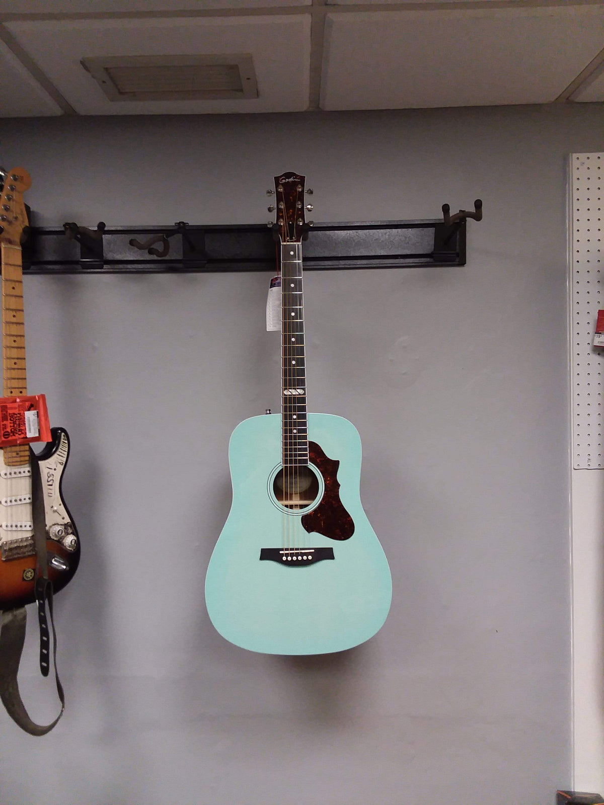 Godin Imperial Laguna Blue GT EQ acoustic guitar with a solid mahogany body, Sitka spruce top, and on-board preamp, displayed against a wall.