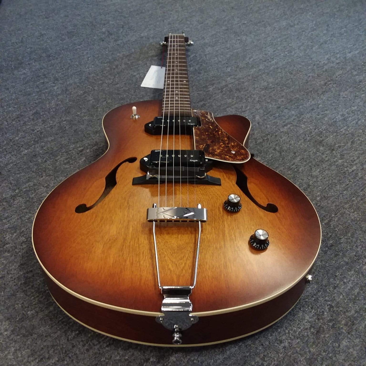 Godin 5th Avenue CW Kingpin II Cognac Burst guitar with P90 pickups lying on grey carpet.