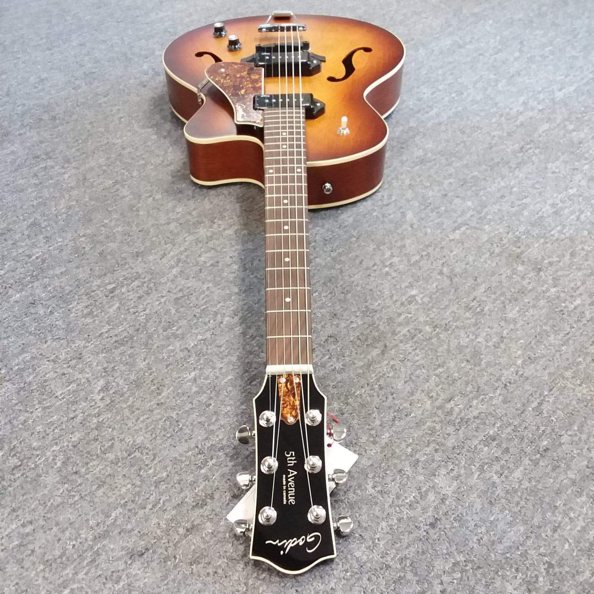 Godin 5th Avenue CW Kingpin II Cognac Burst guitar with a cutaway body design, featuring two Godin Kingpin P90 pickups, lying on the floor.