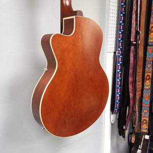 Godin 5th Avenue CW Kingpin II Cognac Burst guitar with vintage-style archtop and P90 pickups, leaning against a white wall.