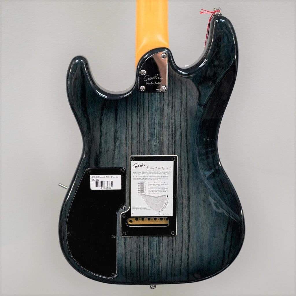The back of the Godin RG3 Passion Lace Sensor Hot Gold Indigo Blue guitar shows a yellow neck, metal neck plate, barcode label, and rectangular panel with tremolo instructions. Includes gig bag.