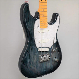 The Godin RG3 Passion in Indigo Blue, featuring three Lace Sensor Hot Gold pickups and chrome hardware, hangs against a plain light gray background. Includes a maple neck and comes with a gig bag.