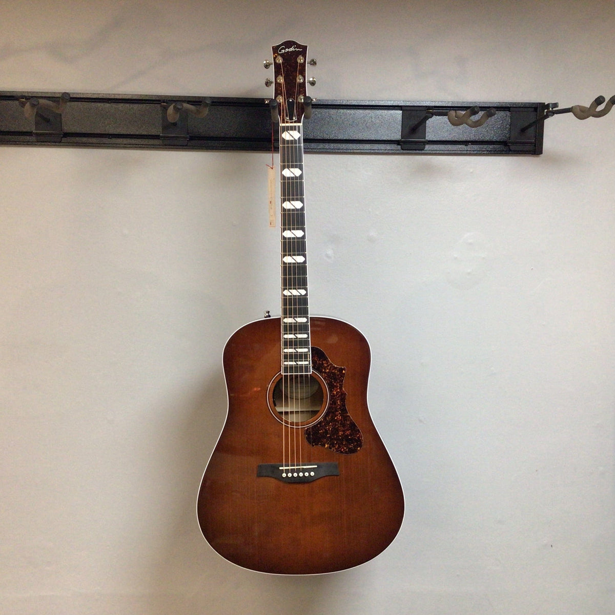 Godin Metropolis LTD Havana Burst HG EQ SF guitar displayed on a wall, highlighting its detailed craftsmanship and premium build.