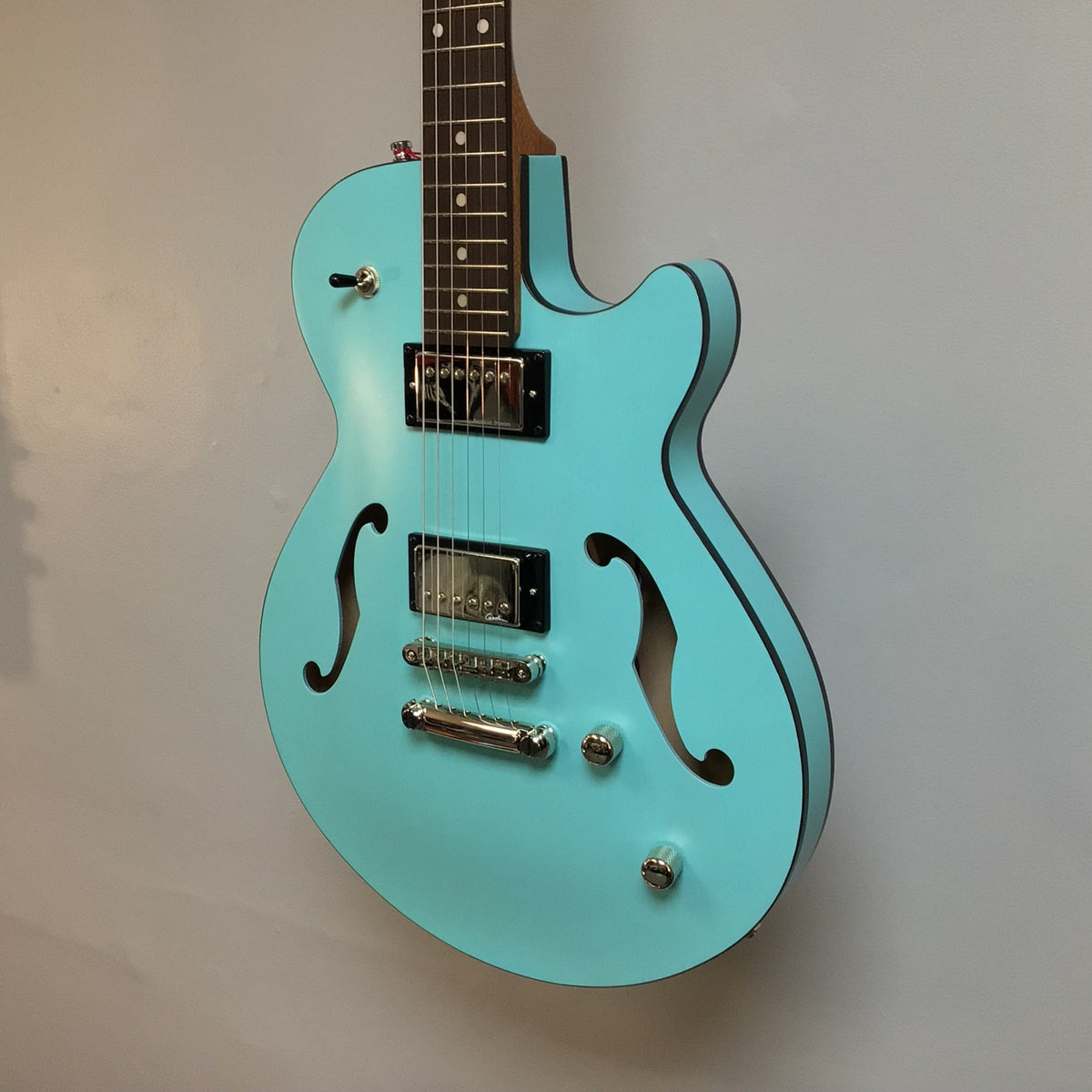 Godin Montreal Premiere HT Laguna Blue Blem w/Gigbag Open Box—semi-hollow body electric guitar with a unique finish, displayed against a wall.