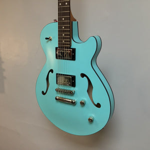 Godin Montreal Premiere HT Laguna Blue Blem w/Gigbag Open Box—semi-hollow body electric guitar with a unique finish, displayed against a wall.
