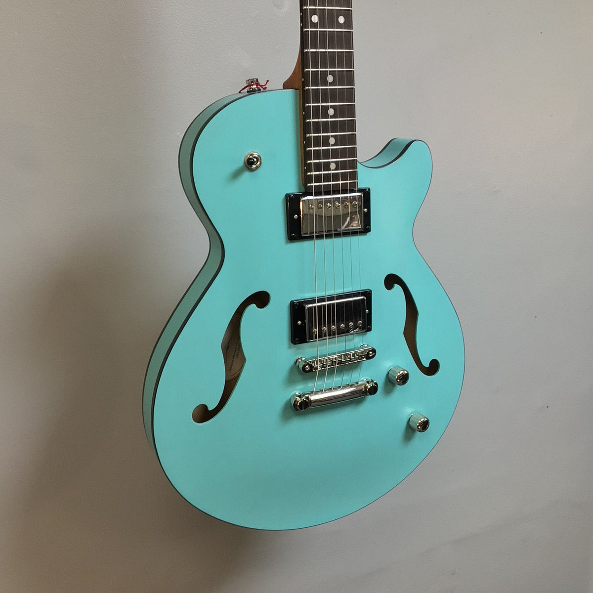 Godin Montreal Premiere HT Laguna Blue guitar with a semi-hollow body and a unique acoustic-inspired finish, displayed on a wall.