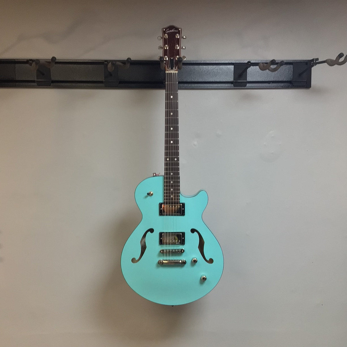 Godin Montreal Premiere HT Laguna Blue Blem w/Gigbag Open Box: Semi-hollow electric guitar with a vibrant blue finish, displayed against a wall.