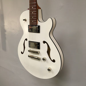 Godin Montreal Premiere HT Trans White electric guitar with black trim and visible strings, displayed against a wall.