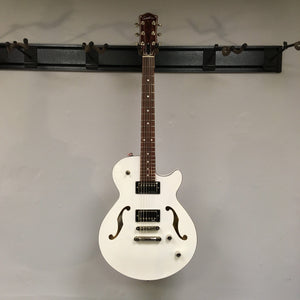 Godin Montreal Premiere HT Trans White guitar on a wall, highlighting its elegant design and build.