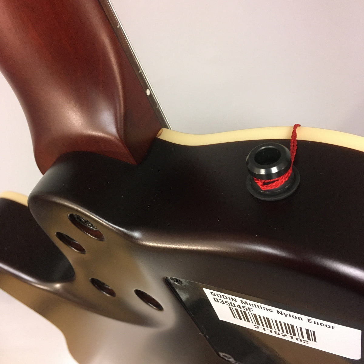 Close-up of a Godin Multiac Nylon Encore SG SF guitar showcasing its cedar top and dual source electronics.