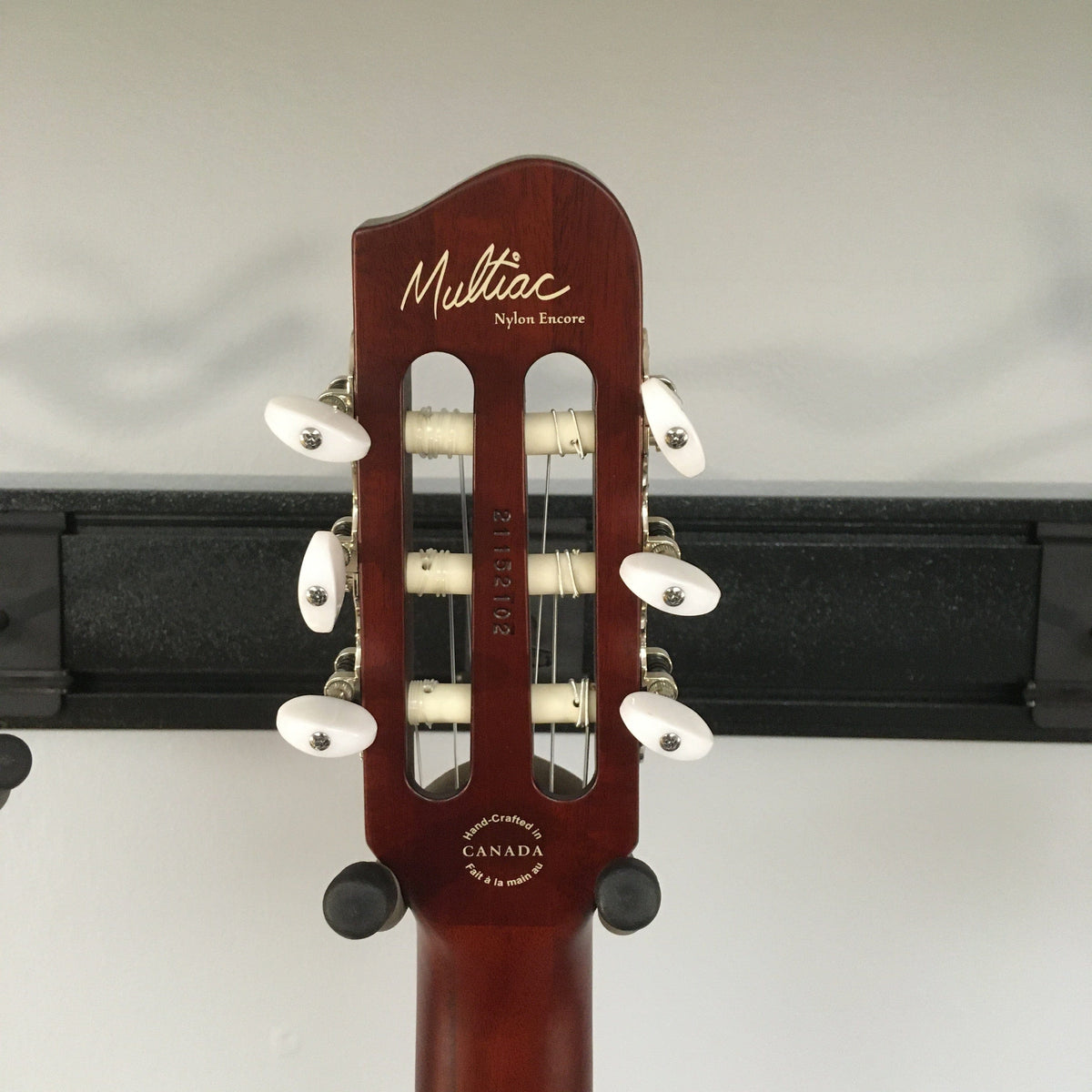 Close-up of a new Godin Multiac Nylon Encore SG SF guitar, highlighting its custom electronics and finish blemishes.